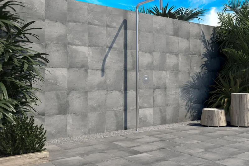 Douche extérieure de piscine devant un mur en carrelage effet pierre grise